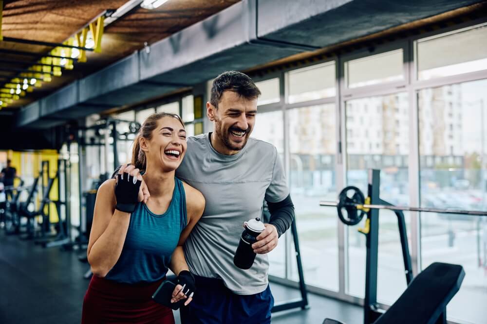 Stress management through exercise Mile High Psychology Example of active stress management through a photograph of man and woman laughing together after exercising in the gym.