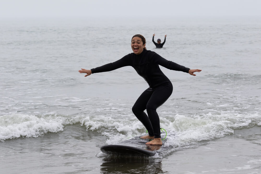 Learning to surf Mile High Psychology Example of recreation as a from of stress management using a photograph of a woman smiling while learning to serve.